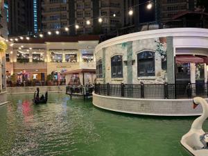 Un río con cisnes en una ciudad de noche. en Park Mckinley West 1BR Balcony near BGC Makati Airport, en Manila