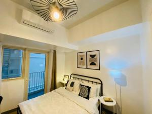 Un dormitorio con una cama y una ventana grande. en Park Mckinley West 1BR Balcony near BGC Makati Airport, en Manila 15 fotos más