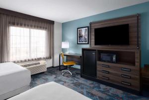 a hotel room with a flat screen tv and a desk at La Quinta by Wyndham Greensboro NC in Greensboro +23 photos