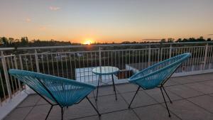two chairs and a table on a balcony with the sunset at Ferienwohnung Lehmann 2 in Wolfenbüttel