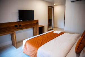 a bedroom with a bed and a flat screen tv at Hotel Orange in Bhubaneshwar