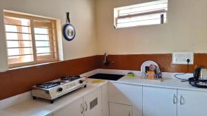 a kitchen with a stove and a counter top at Golden Nest Home Stay in Mysore