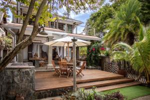 a wooden deck with chairs and an umbrella at Tamarin Paradise Bay Villa 3 chambres sur la plage in Tamarin