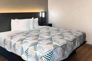 1 dormitorio con 1 cama con edredón blanco y negro en Motel 6 Cheyenne, WY, en Cheyenne
