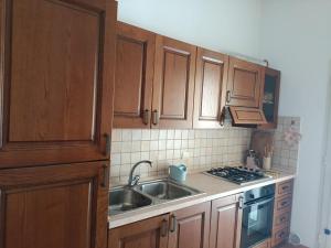 a kitchen with wooden cabinets and a sink and a stove at VILLALoddo2 sud Tertenia in Tertenìa