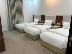 a hotel room with four beds in a room at الغاف للشقق المخدومة in Sarat Abidah +14 photos