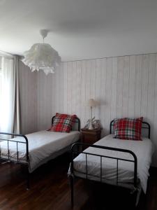 a bedroom with two beds and a chandelier at Gîte breton au bord du GR34 in Landunvez