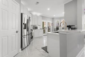 une cuisine avec des armoires blanches et un réfrigérateur en acier inoxydable dans l'établissement Gulfport Arcade Condo, à Gulfport