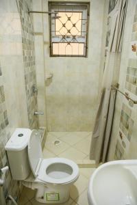 a bathroom with a toilet and a shower with a window at AMP HOME STAY NYALI PRIVATE ROOM WITH POOL in Mombasa