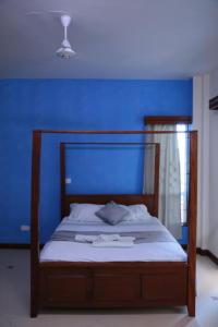 a bedroom with a bed with a blue wall at AMP HOME STAY NYALI PRIVATE ROOM WITH POOL in Mombasa