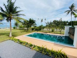 a swimming pool in front of a house with palm trees at Klai house beach pool villa , Klai ,Thasala, Nakhon si Thammarat in Ban Phang Pling