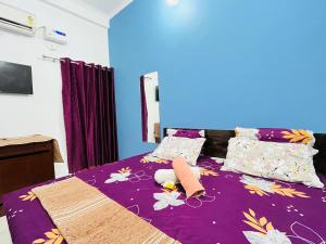 un letto con coperta viola e cuscini sopra di Maa vaishno paying guest house a Ayodhya