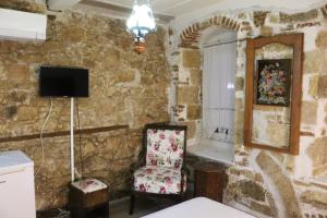 Ein Zimmer mit einer Steinwand, in dem ein Stuhl und ein Fernseher stehen. in der Unterkunft şekercigiller in Ayvalık