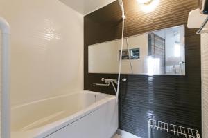 Un baño con bañera blanca y pared negra. en -W- Vacation Rental, en Nagoya 15 fotos más