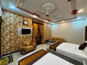 a bedroom with two beds and two chairs and a tv at Metro One Hotel in Lahore