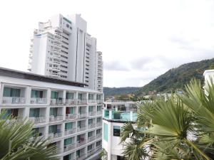 a tall white building with a mountain in the background at Boomerang Inn in Patong Beach