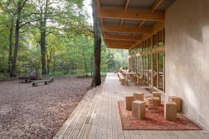 a building with a porch with tables and benches at Youza ecolodge cabanes dans les arbres in La Couture-Boussey