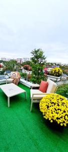 a group of chairs and tables on a green floor with flowers at Penthouse View Aeroport Iasi in Iaşi