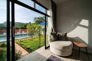 salon z krzesłem i dużym oknem w obiekcie Pool Villa Alawan Krabi Klong Muang R2 w mieście Klong Muang Beach