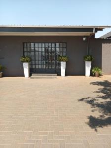 a building with three potted plants in front of a door at African Kingdom Guest House in Boksburg