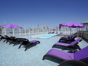 a row of purple lounge chairs and a swimming pool at Masaya By Emerald in Erbil