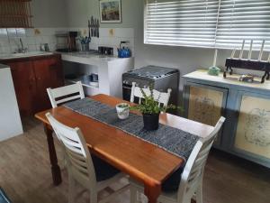 a kitchen with a wooden table with white chairs at Babylons Tower Cottage in Caledon +14 photos