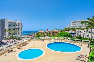 a large swimming pool with chairs and the ocean at Luxury Copacabana in Costa de Adeje