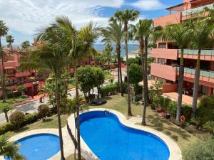 an apartment with a swimming pool and palm trees at Las Salinas in Estepona