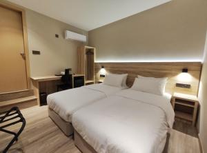 a bedroom with a large white bed and a chair at Nuvo Hotel in Bandar Seri Begawan