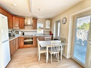 a kitchen with a table and chairs in a kitchen at No1 Glan Nodwydd in Pentraeth