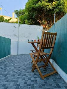 einem Holzstuhl neben einem Tisch auf einer Terrasse in der Unterkunft Casa ao centro - Apartamento Angrego in Angra do Heroísmo