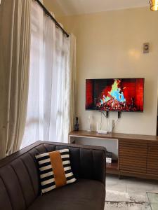 a living room with a couch and a flat screen tv at beautifully furnished one bedroom apartment in vok off nyali road in Mombasa +3 photos