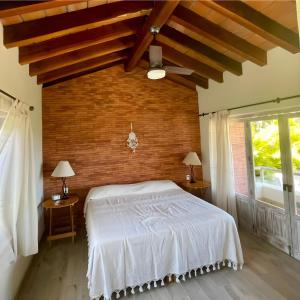 a bedroom with a white bed and a brick wall at Casa Cerritos in Sayulita