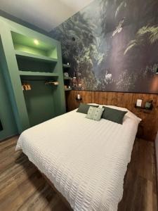 a bedroom with a white bed with a painting on the wall at Jardin Secret in Groffliers