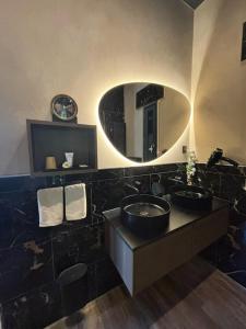 a bathroom with two sinks and a round mirror at Jardin Secret in Groffliers