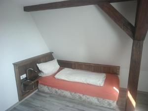 a small bed in a room with a wooden headboard at Pension Völkner in Bautzen