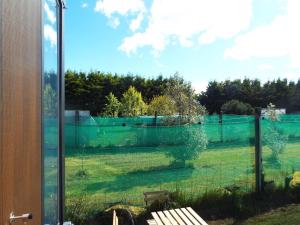 uma vista para um campo através de uma janela de vidro em Okuti Cottage by Tiny Away em Wairau Valley