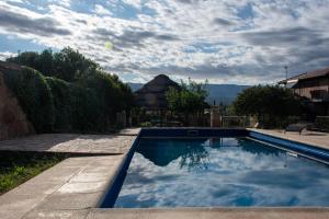 een zwembad in een tuin met een bewolkte hemel bij Altos de Brochero Cabañas & Padel in Villa Cura Brochero