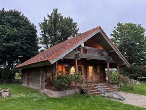 a small log cabin with a porch on a field at Kangru Holiday Home in Vanamõisa +44 photos