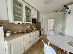 a kitchen with white cabinets and a table with chairs at FeWo Büdingen - Landhaus in Büdingen