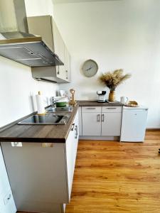 a kitchen with white cabinets and a sink and a clock at Stadtquartier Luckenwalde in Luckenwalde