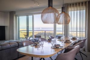 a dining room with a table and chairs and a large window at The Bay luxurious full sea view in Cadzand