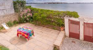 a table with a colorful umbrella on a patio next to the beach at RÉF 407 - LARMOR PLAGE Maison de famille pleine vue mer in Larmor-Plage