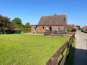a house with a fence in front of a yard at Haus Alexandra in Dornum