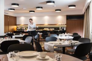 a woman is standing in a dining room with tables at Fraser Suites Geneva - Serviced Apartments in Geneva
