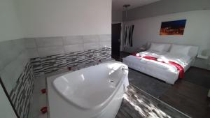 a bathroom with a bath tub next to a bed at Arcanum Apartman in Makó