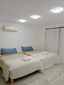 2 camas en una habitación blanca con almohadas azules en Hostal Dream gunther, en Cancún