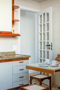 una cocina con armarios blancos y una mesa con taburetes en Agradável apartamento próximo a Praia de Ipanema, en Río de Janeiro