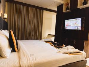 a hotel room with a bed and a tv at HOTEL JBS Minerva Grand in Khammam