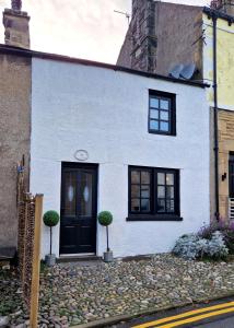una casa bianca con porta nera e finestre di Historic 17th-Century Cottage with Hot Tub in Charming Heysham a Heysham